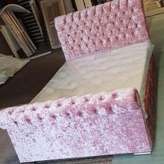 an upholstered bed with pink velvet headboard and foot board in a warehouse