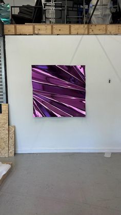 an abstract painting is hanging on the wall in a room with unfinished walls and concrete flooring