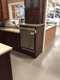 a kitchen with brown cabinets and white counter tops in a store or showroom area