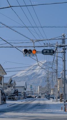 an intersection with traffic lights and snow covered mountains in the background