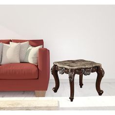 a red couch sitting next to a table on top of a hard wood floor covered in pillows