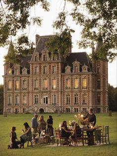 a group of people sitting around a table in front of a large building