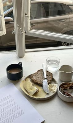 a plate with some food on it next to a cup of coffee and a paper