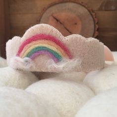 there is a small toy with a rainbow on it's head and some white fluffy balls