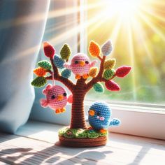 a crocheted tree with two birds sitting on it next to a window sill