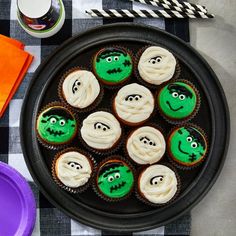 cupcakes decorated with green icing and white frosting are on a black plate