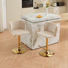 two chairs sitting at a kitchen island with marble counter top and gold accents on the legs