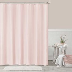 a pink shower curtain in a bathroom next to a white rug and potted plant