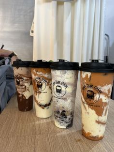 three different types of coffee cups sitting on top of a wooden table next to each other