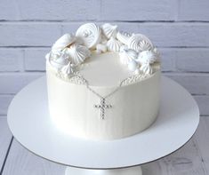 a cake decorated with shells and a cross is on a white plate next to a brick wall