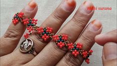 a woman's hand with red and blue beaded rings on her fingers,