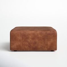 a brown leather ottoman sitting on top of a white floor