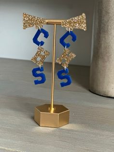 a pair of blue and gold earrings sitting on top of a stand