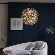 a white couch sitting under a chandelier in a living room next to a wall