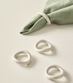 three white rings sitting on top of a table next to a green napkin and a pair of scissors