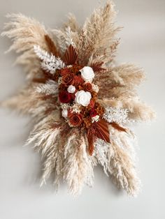 an arrangement of dried flowers and feathers on a white background