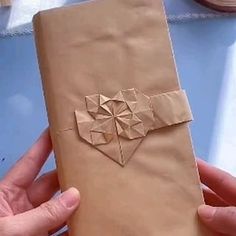 a person is holding a brown paper bag with an origami design on it