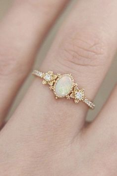 a woman's hand with a ring that has an opal and diamonds on it