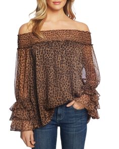 a woman wearing a leopard print top with sheer sleeves and an off the shoulder neckline