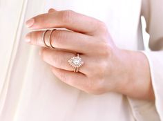 a woman's hand wearing a gold ring with a flower on the middle, and a diamond in the middle