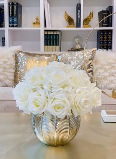 a vase filled with white flowers sitting on top of a table next to a couch