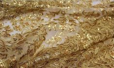 gold sequins on white fabric with golden flowers and leaves in the center, close up