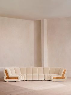 a white couch sitting on top of a hard wood floor next to a tall wall