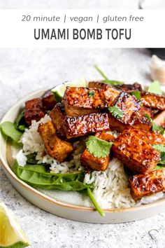 a white plate topped with tofu and rice next to a glass of sauce on the side