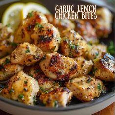 garlic lemon chicken bites in a bowl with lemon wedges