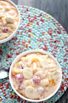 two bowls filled with food sitting on top of a colorful place mat next to a spoon