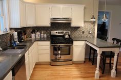 a kitchen with white cabinets and stainless steel appliances in the center, along with hardwood floors