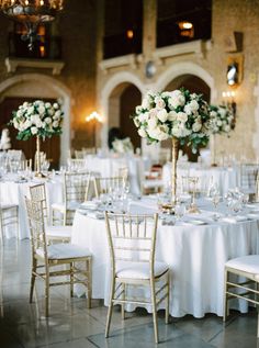 the tables are set up with white linens and gold chairs for an elegant wedding reception