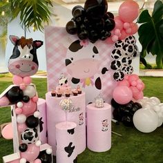 a pink and black cow themed birthday party with balloons, decorations, and other items