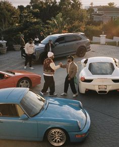 several people are standing in front of some cars