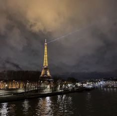 the eiffel tower is lit up at night with lights reflecting in the water