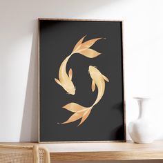 a framed photograph of two gold fish on a black background with a white vase next to it