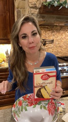 a woman holding up a box of cake mix