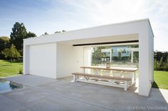 a white house with a picnic table in the front yard and swimming pool behind it