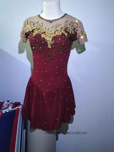 a red dress with gold sequins and beads on the neckline is displayed in front of a white wall