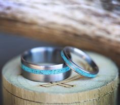 two wedding rings sitting on top of a piece of wood