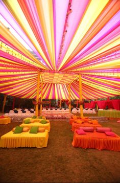 an outdoor event decorated with colorful lights and draping on the ceiling, couches and tables