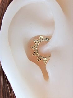 a pair of gold earrings sitting on top of a white plate