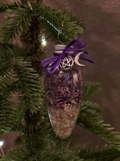 an ornament hanging from a christmas tree decorated with purple and silver decorations,