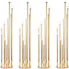 four tall gold candles are in the shape of poles with white candles on each end