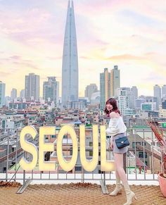 a woman standing on top of a roof with the word seoul in front of her