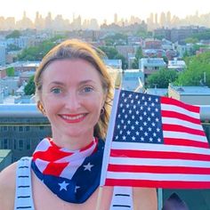 a woman holding an american flag on top of a building