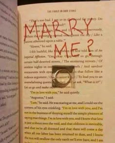 an open book with the words marry me? written in red and black ink on it