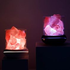 two different types of rocks in a glass bowl on top of a black stand with a purple light behind them