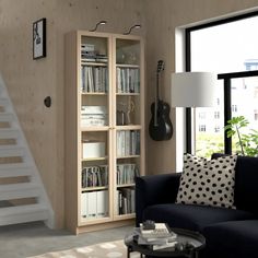 a living room filled with furniture and a book shelf next to a stair case in front of a window