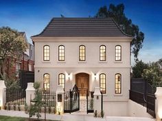 a white two story house with lots of windows and lights on the front door is lit up at night